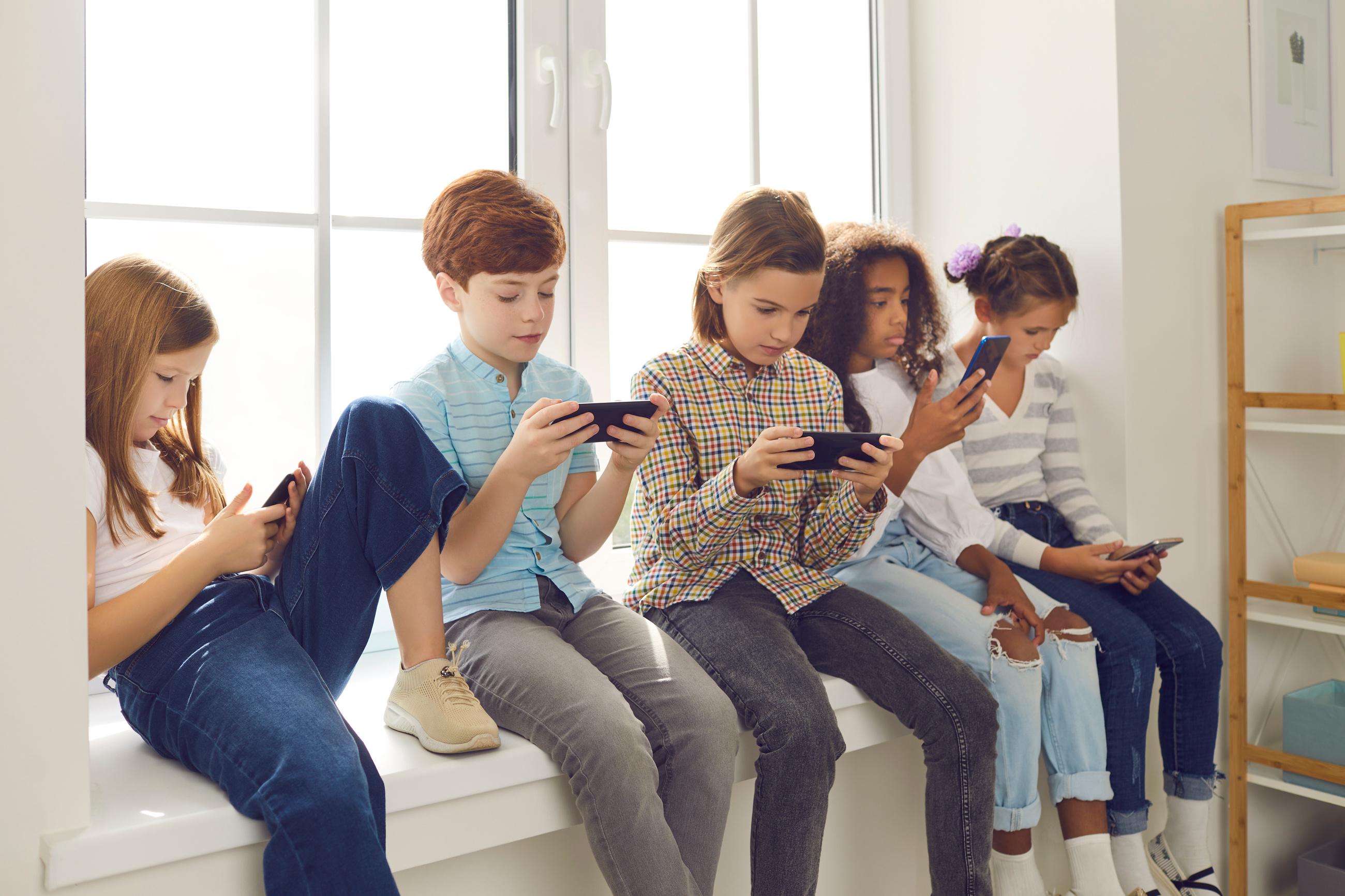 Children Sitting on Windowsill, Playing Online Games on Mobile Phones and Ignoring Each Other